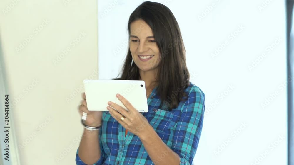 Young, happy woman with tablet and keys standing at her new home
Young, happy woman with tablet and keys standing at her new home