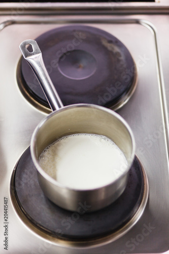 steel saucepan with milk on an electric stove