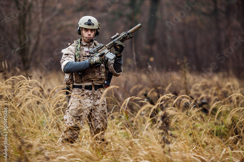soldier with rifle in full gear. Military man on the background of nature.