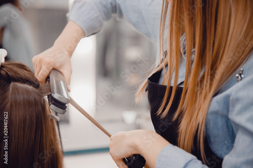 Close-up of master hairstylist ironing for straightening hair restores keratin and straightens hair.