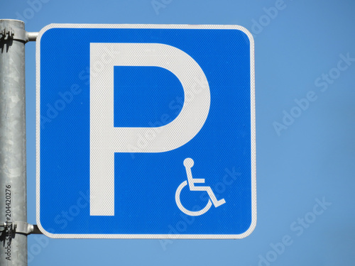 Disabled parking space road sign isolated on clear blue sky background. Handicapped parking spot, sign of wheelchair