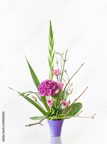 Artistic floral decoration on a table in a ceramic flowerpot isolated on white background.