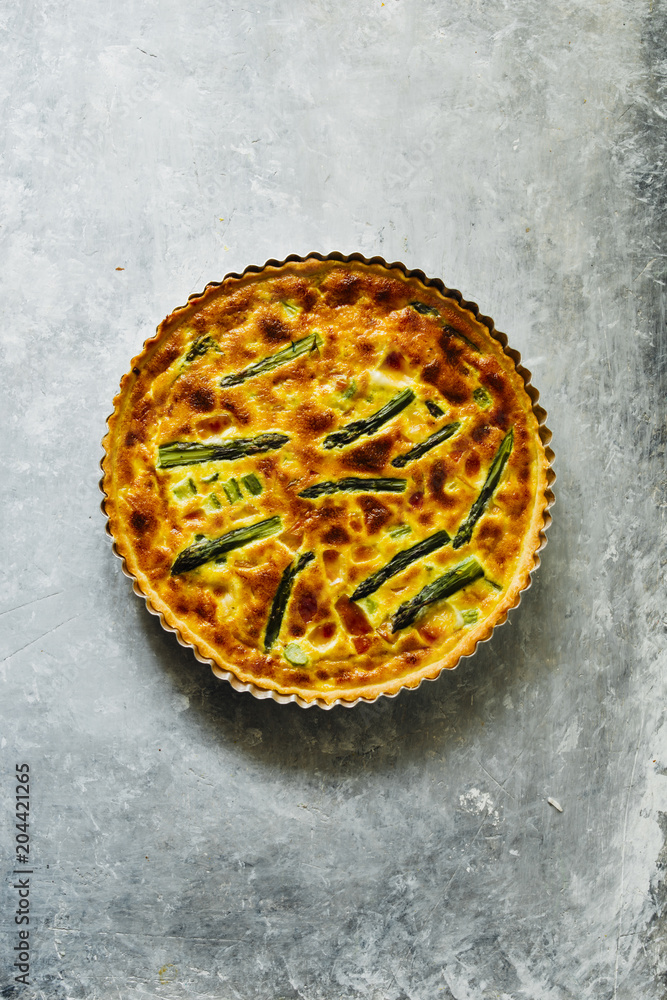 Quiche with green asparagus
, egg, cream, scamorza cheese and spec ham, round shaped on an aluminium mold, top view over a gray emerald board. Quiche with green asparagus
, egg, cream, scamorza cheese and spec ham, round shaped on an aluminium mold, top view over a gray emerald board.