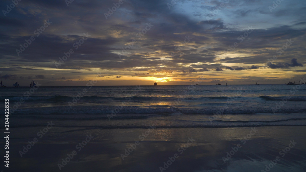 Sunset over the sea in the background boats,sailing boat, orange sky and islands. Sailing boats at sunset in the sea. Travel concept. Beautiful serene scene. Philippines, Boracay. Travel concept.