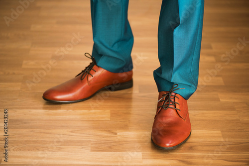 Man wearing shoes on wooden floor. Clothing concept, groom getting ready before ceremony. Body detail of businessman.