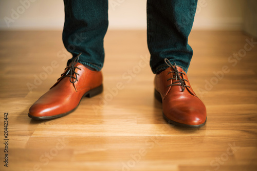 Man wearing shoes on wooden floor. Clothing concept, groom getting ready before ceremony. Body detail of businessman.