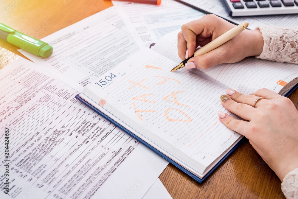 Female hands making memo about tax pay in diary Female hands making memo about tax pay in diary
