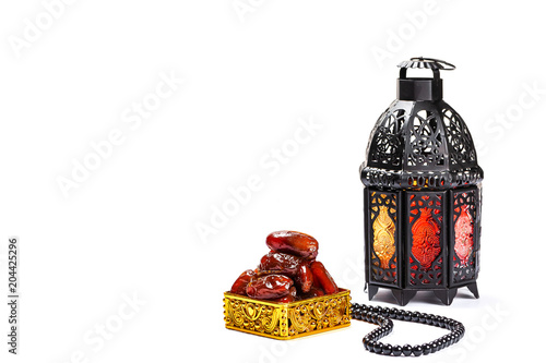 The Muslim feast of the holy month of Ramadan Kareem. Beautiful background with a shining lantern Fanus and dried dates on white. Free space for your text