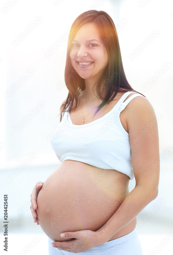 closeup of a pregnant woman putting her hands on her tummy.