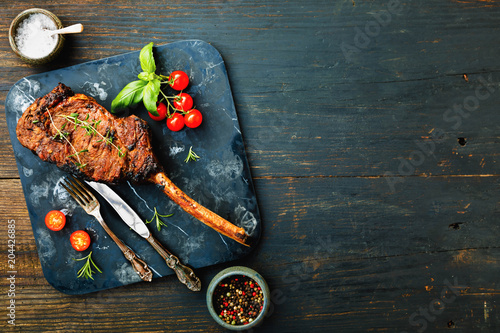 Sliced barbecued tomahawk rib tip with rosemary, salt and herbs on dark background