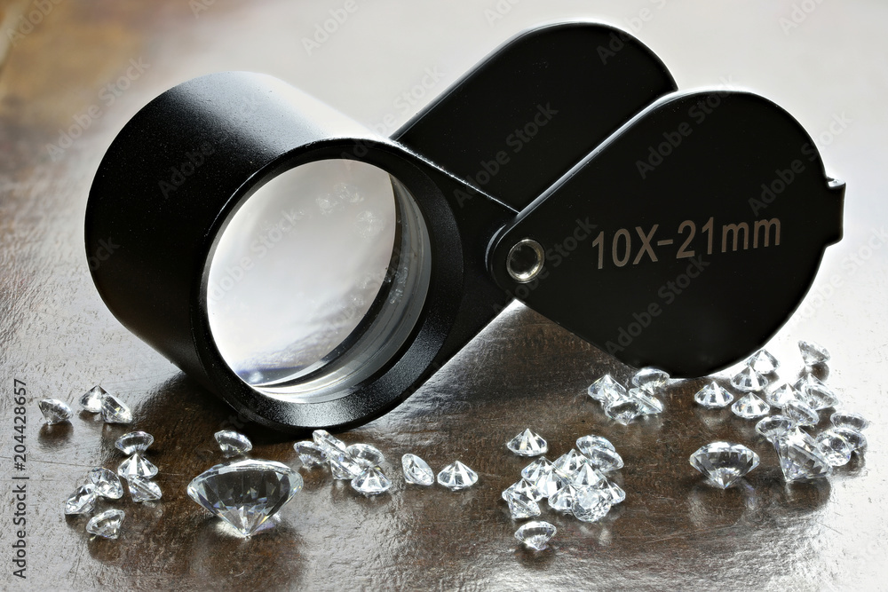 brilliant cut diamonds with folding magnifier on wooden background