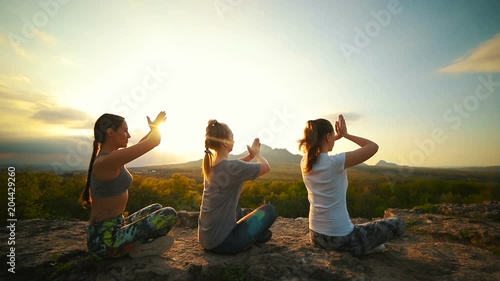 A group of girls at sunset are engaged in yoga. Slow motion