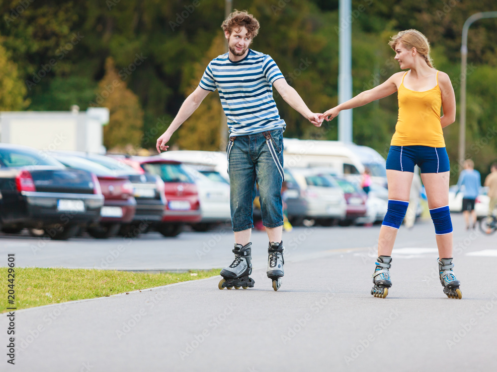 Young couple on roller skates riding outdoors Young couple on roller skates riding outdoors