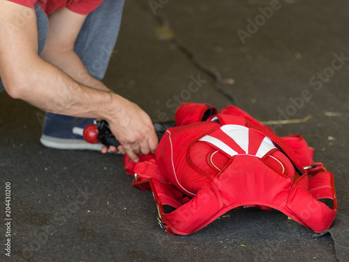 Skydiver Folding Up His Red Parachute on the Ground