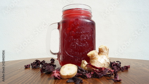 Agua de jamaica con jengibre en frasco de vidrio sobre mesa de madera con fondo blanco photo