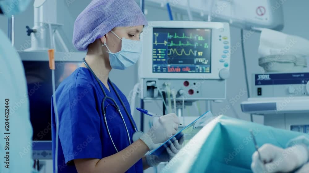 In the Hospital Operating Room Anesthesiologist Looks and Monitors and Controls Patient's Vital Signs, Nodding to a Chief Surgeon. Shot on RED EPIC-W 8K Helium Cinema Camera. In the Hospital Operating Room Anesthesiologist Looks and Monitors and Controls Patient's Vital Signs, Nodding to a Chief Surgeon. Shot on RED EPIC-W 8K Helium Cinema Camera.
