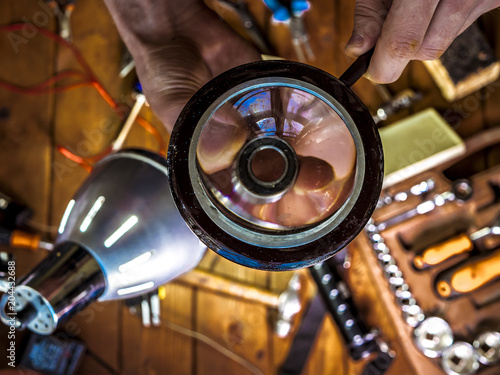 hands with magnifier looking at bearing in the workshop over the table