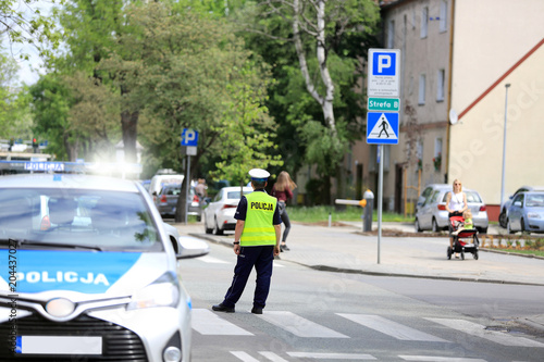 Policjant z samochodem służbowym na skrzyżowaniu ulic w centrum miasta Opole.