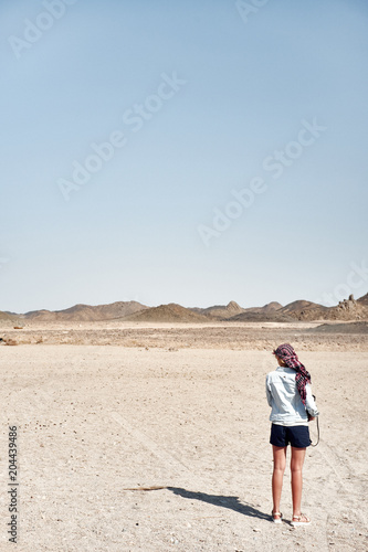 Woman in the desert is standing with her back looking silhouetted
