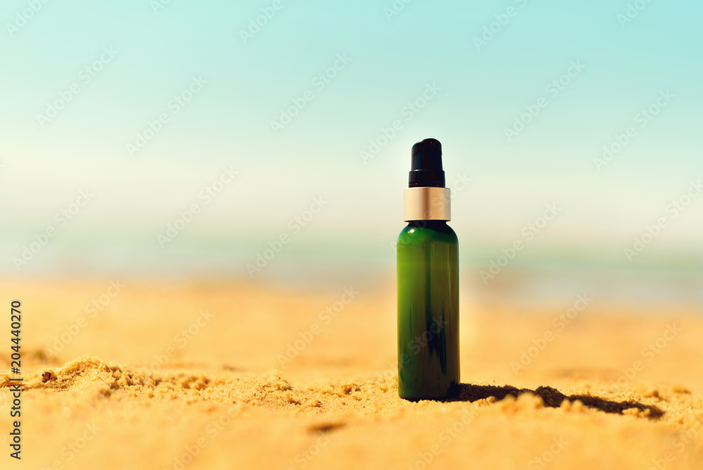Bottle of sunscreen in sand against sea background with copyspace. Vacation and travel wallpaper. Skin care concept. Bottle of sunscreen in sand against sea background with copyspace. Vacation and travel wallpaper. Skin care concept.
