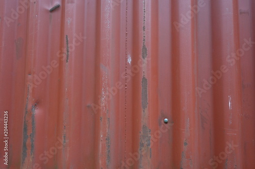 Corrugated metal sheet serves as a fence, view horizontal to vertical stripes