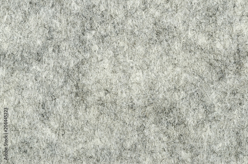 Gray felt surface. Textile material, made of matted synthetic fibers. White, gray and black acrylic pressed together. Fabric pattern. Background. Macro photography from above. 