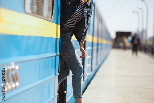 cropped shot of stylish woman going out from train at outdoor subway station