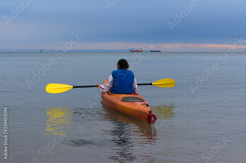 La muchacha en su kayaks observa la dirección a seguir.