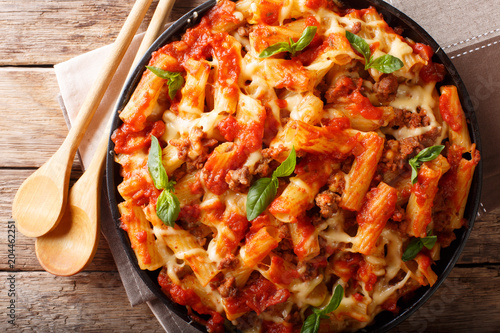 Casserole ziti pasta with minced meat, tomatoes, herbs and cheese close-up. Horizontal top view photo