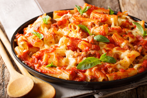 Spicy pasta ziti with minced meat, tomatoes, herbs and cheese close-up. horizontal