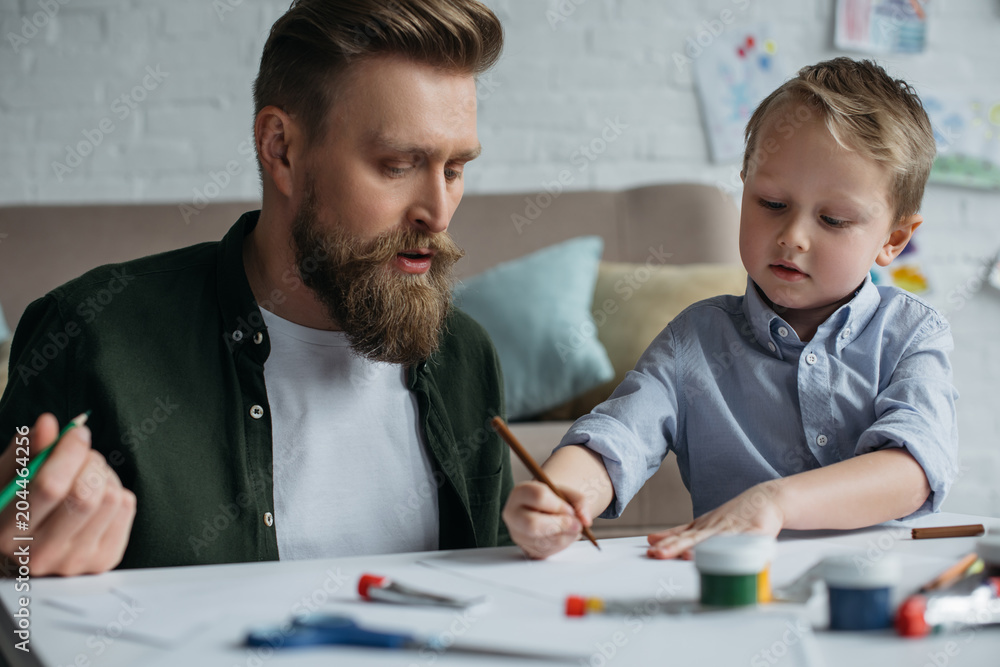 father and cute little son with colorful pencils drawing pictures together at home father and cute little son with colorful pencils drawing pictures together at home