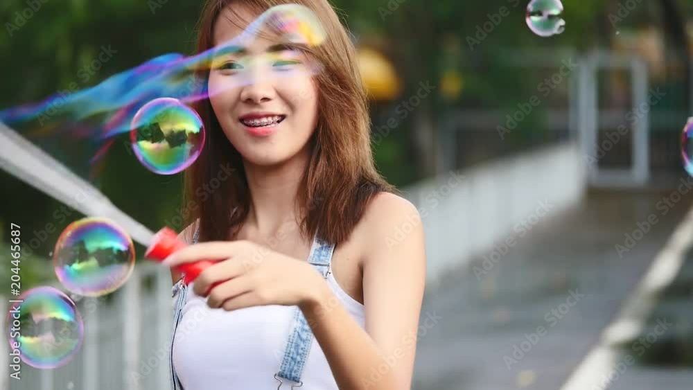 Young beautiful happy woman making soap bubbles in park Young beautiful happy woman making soap bubbles in park