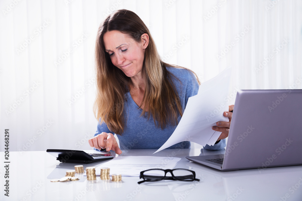 Businesswoman Calculating Invoice In Office Businesswoman Calculating Invoice In Office