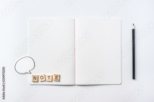 Design concept - Top view of notebook blank page, black pencil and wood cube isolated on white background for mockup