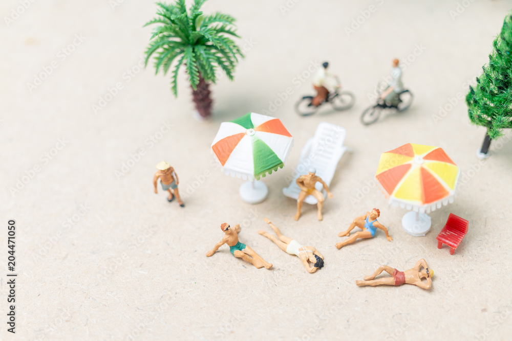 Miniature people wearing swimsuit relaxing on the beach Miniature people wearing swimsuit relaxing on the beach