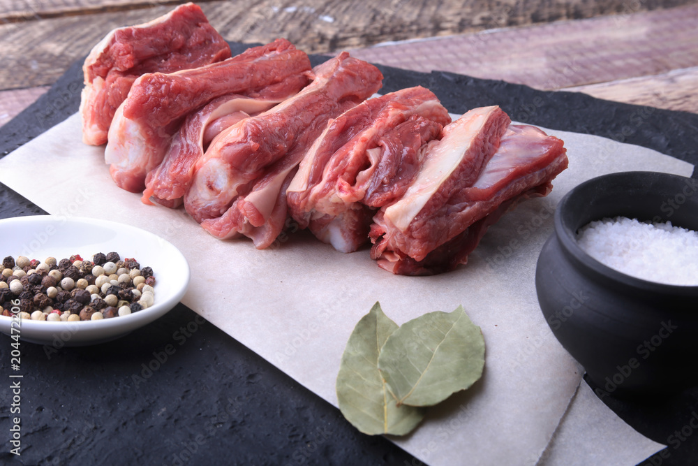Raw fresh meat, uncooked lamb or beef ribs with pepper, garlic, salt and spices on dark stone background, Ready for cooking. copy space.
