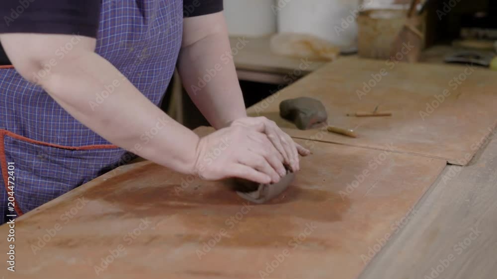 Close up shot of specialist kneading the clay before working on the pottery wheel. Close up shot of specialist kneading the clay before working on the pottery wheel.