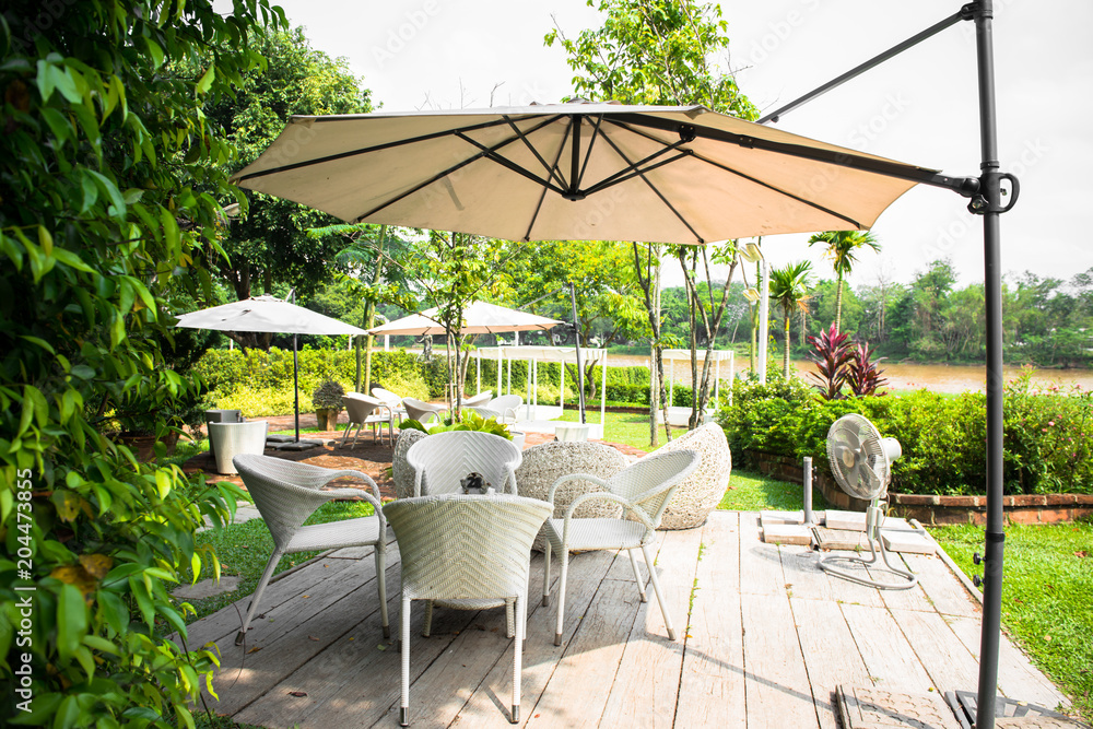 Outdoor furniture, rattan chairs and glass table on the terrace in the garden. - obrazy, fototapety, plakaty 
