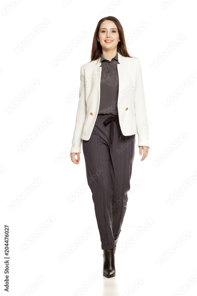 Young businesswoman in pants and suit walking on white background Young businesswoman in pants and suit walking on white background