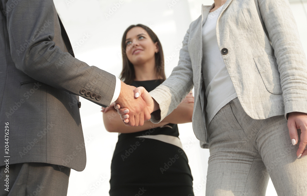 © ASDF - Businesspeople  shaking hands against room with large window loo