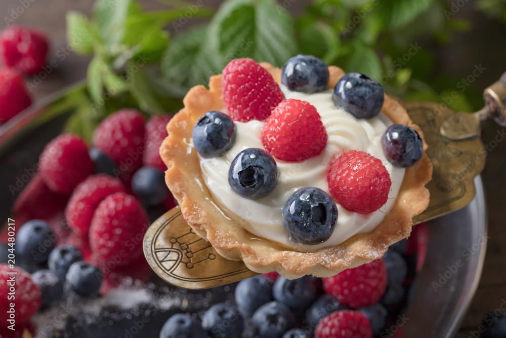 Dessert tarts with raspberries and blueberries on a wooden table. Dessert tarts with raspberries and blueberries on a wooden table.