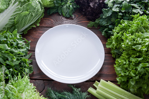 Green, juicy lettuce leaves in assortment with a white plate in the center view from above
