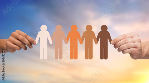 population, race and ethnicity concept - multiracial couple hands holding chain of people pictogram over evening sky background photo