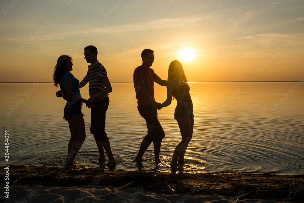 Fototapeta premium Young people, guys and girls, students are dancing on the beach at sunset background