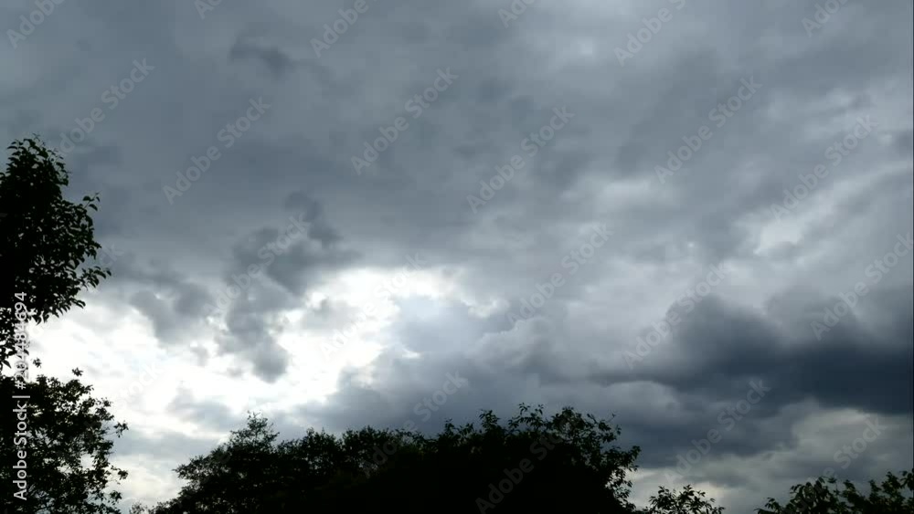 A cloudy day. Gray clouds quickly move across the sky against the background of the forest and trees. A cloudy day. Gray clouds quickly move across the sky against the background of the forest and trees.