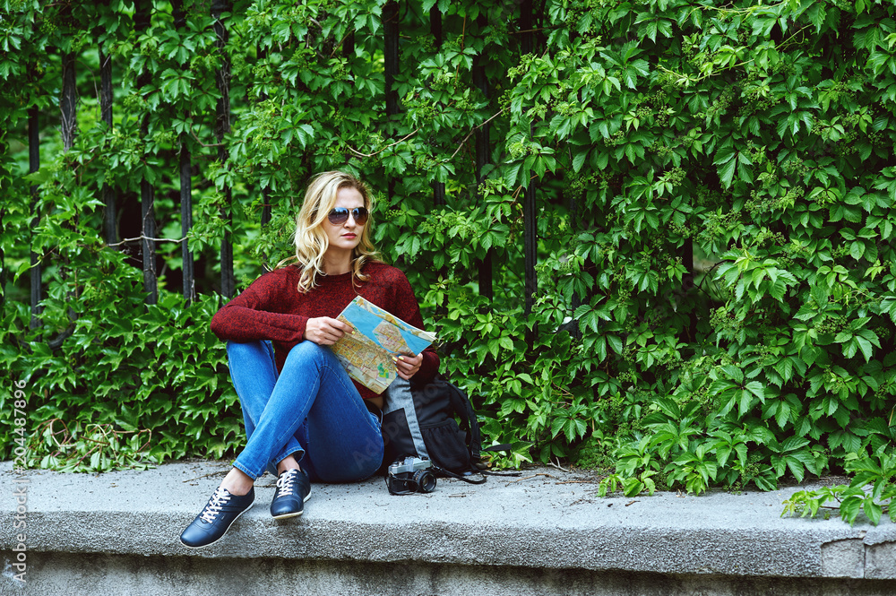 Young tourist woman on city street . Stylish lady in jeans and Burgundy sweater in the city . The concept of casual wear for walking and Hiking Young tourist woman on city street . Stylish lady in jeans and Burgundy sweater in the city . The concept of casual wear for walking and Hiking