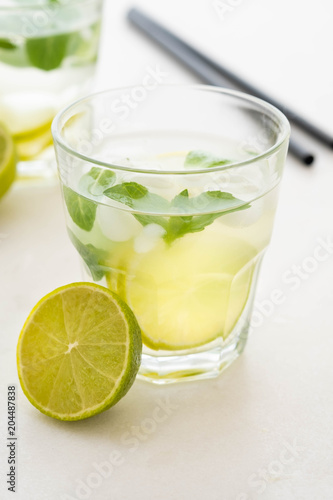 Mojito cocktail on a white marble background. Mint, lime, ice ingredients and bar shaker.