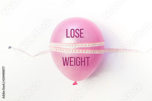 Balloon tied measuring tape on white background. Weight loss, slim body, healthy lifestyle concept. The waist measurement.