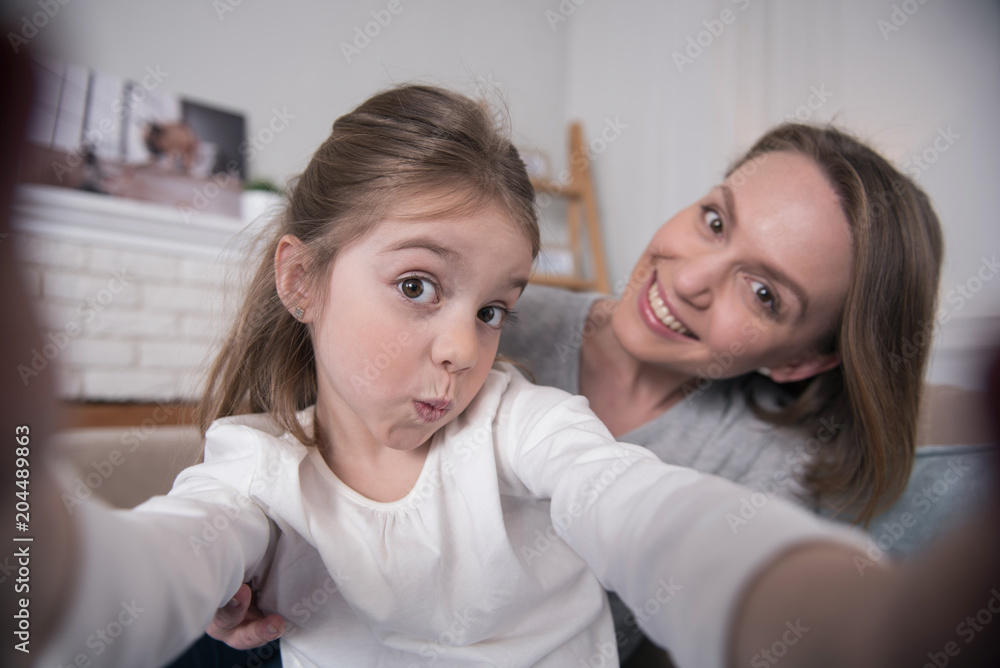 Future photographer. Attractive glad mummy and daughter smiling and taking selfies Future photographer. Attractive glad mummy and daughter smiling and taking selfies