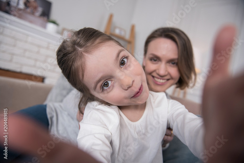 Photographing. Beautiful content mummy and daughter smiling and taking selfies